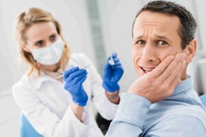 Patient holding cheek with tooth pain during a dental exam.